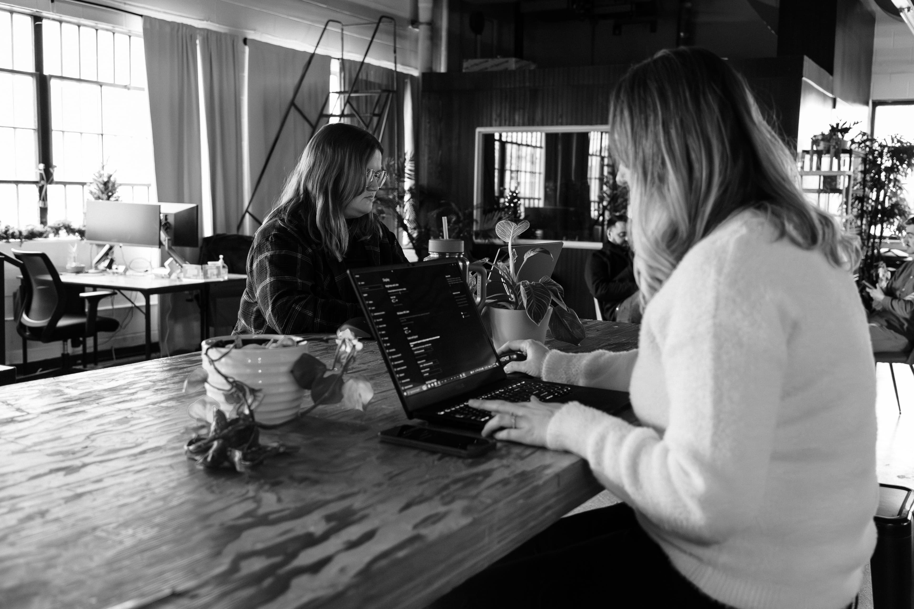 Design intern Brook and Art Director Ali sitting at a table working on laptops